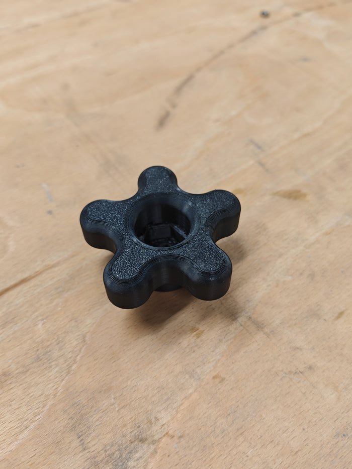 Molette noire à six lobes imprimée en 3D sur un établi